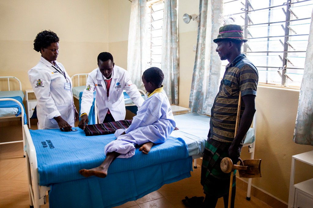 A nurse and pharmacist admit 10-year old Lopeto Losile to the new ward of the Chemolingot Sub-County Hospital. Losile’s father observes the process. Photo by Natalia Jidovanu for Northeastern University