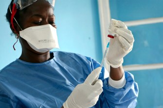 In this photo taken Wednesday, May 30, 2018, a healthcare worker from the World Health Organization prepares vaccines to give to front line aid workers, in Mbandaka, Congo. For the first time since the Ebola virus was identified more than 40 years ago, a vaccine has been dispatched to front line health workers in an attempt to combat the epidemic from the onset. AP Photo/Sam Mednick