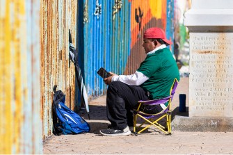 A migrant sits in front of a wall in Tijuana