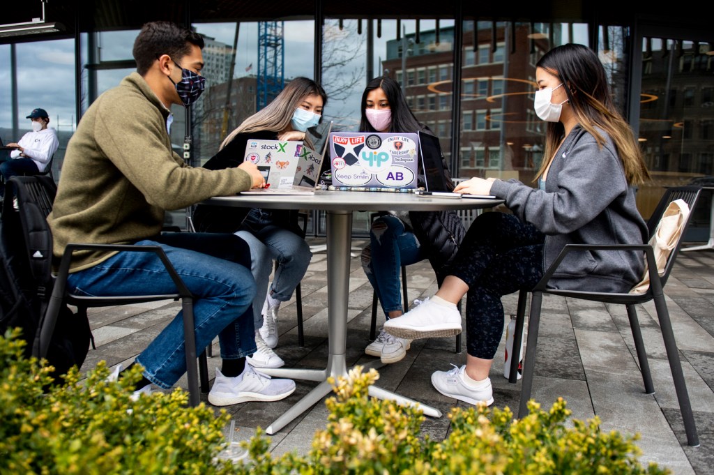 Northeastern students Eva Kuruvilla, Debby Nguyen, Sohum Sheth and Sophia Tan work on a laptop on their Snapchat-like nutrition app for senior citizens, called EatRight.