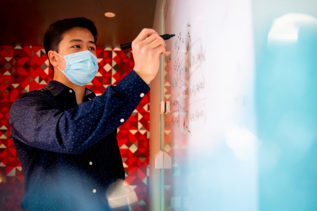 David Liu writes on his blackboard