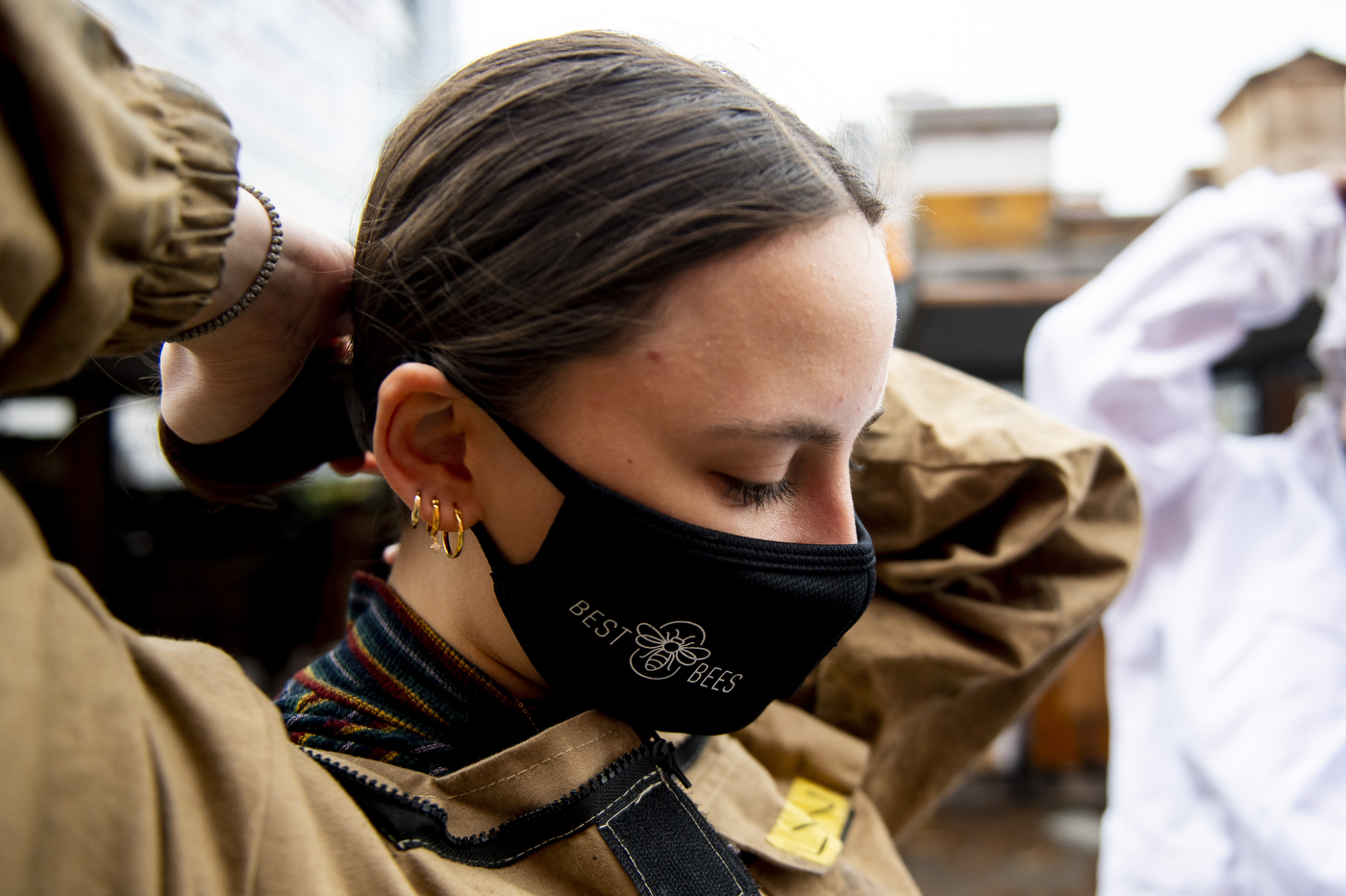 A woman putting on a beekeeping suit