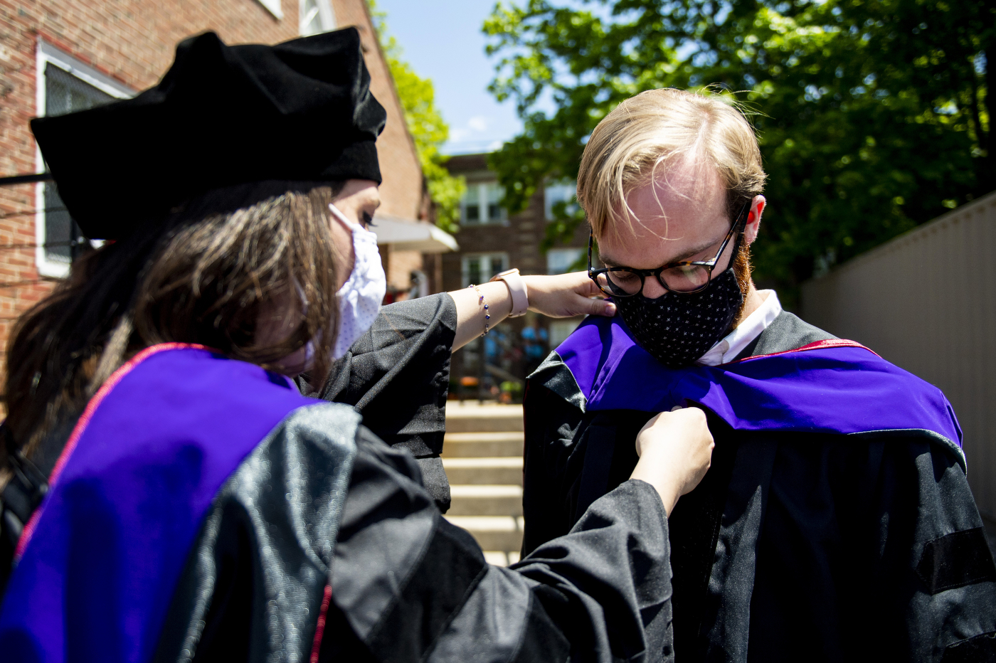 Students and faculty putting on graduation gowns.