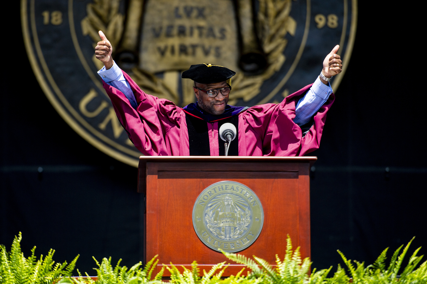 Speaker at lectern with arms raised in celebration