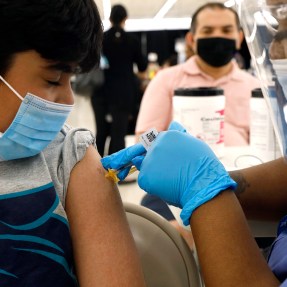 Shivam Patel, 13, receives his first Pfizer COVID-19 vaccination from nurse Diawna Jenkins as his father, Rajesh Patel, observes from the background at the Cook County Public Health Department on May 13, 2021, in Des Plaines, Ill. AP Photo by Shafkat Anowar