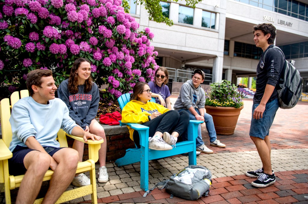 A group of mechanical engineering students hang out in front of Snell Library.