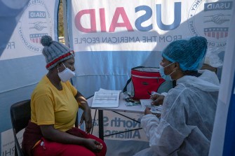 A health care worker in a mask talks to a masked woman