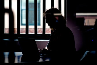 A student sits in a dimly-lit room.