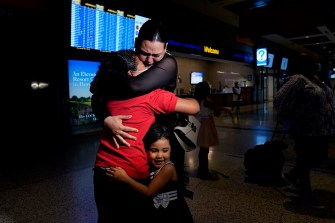 A mother embraces her two daughters