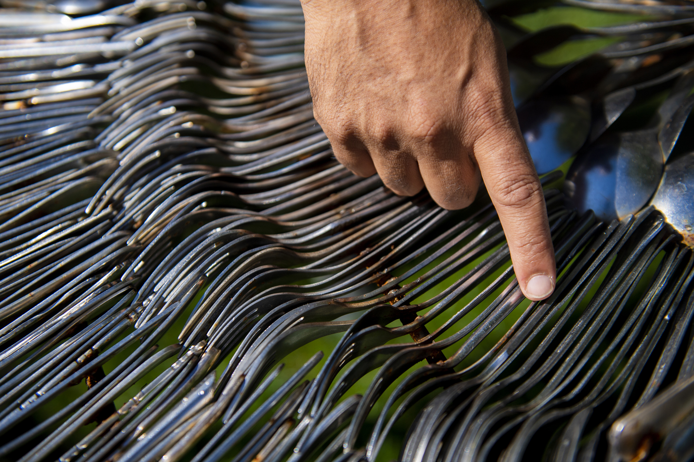 hand pointing to forks lined up against each other in art installation