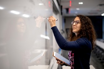 iva halacheva writing on whiteboard as part of her postdoctoral program studies