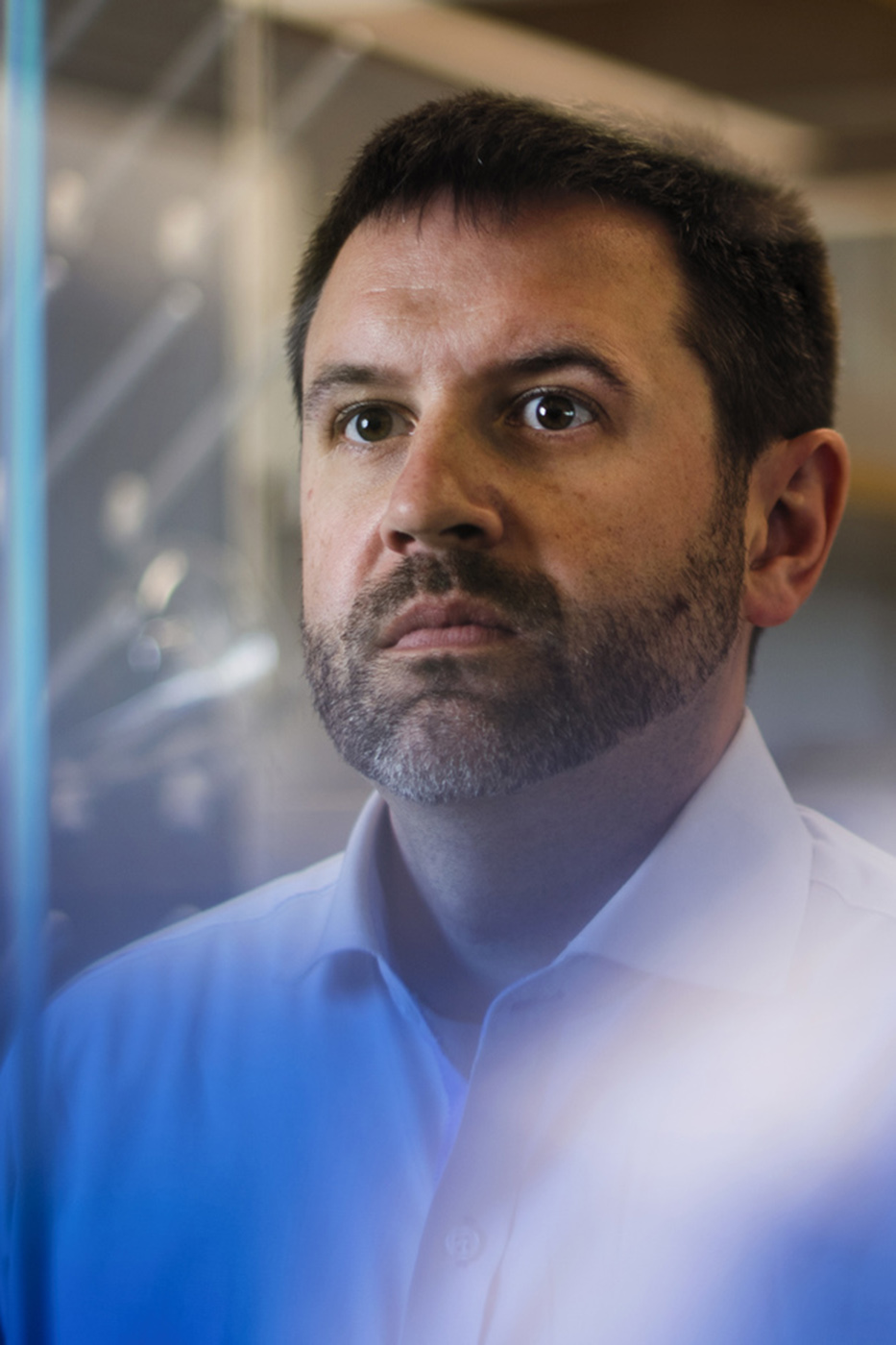 man with dark hair and beard looking serious