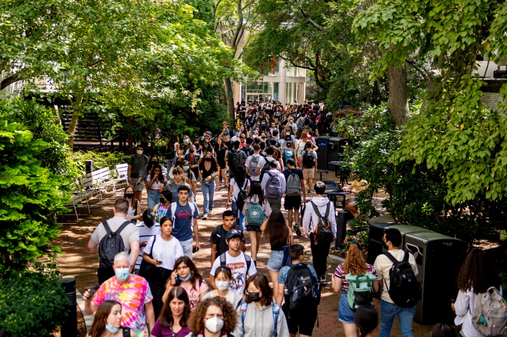 masked and unmasked northeastern students walking on campus