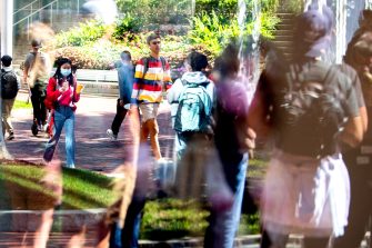 reflection in window of northeastern students walking on campus