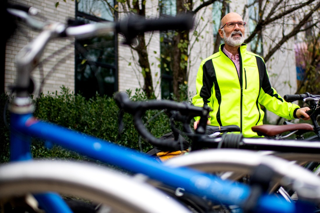 Peter Furth wearing a neon green jacket standing next to his bike. 