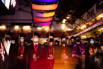 People in graduation caps and gowns stand in a row