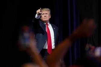 donald trump in suit and red tie pointing into the distance