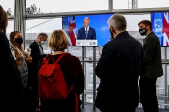 journalists watch joe biden cop26 speech on a tv