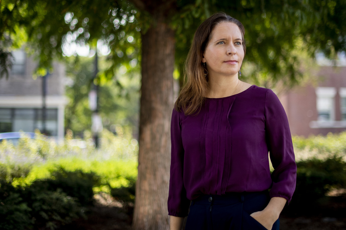 woman standing in front of tree wearing purple shirt