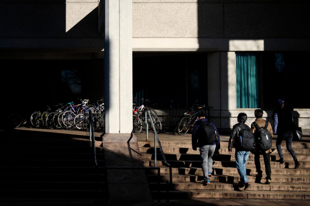 Students walks through a patch of light outside of Snell Library.