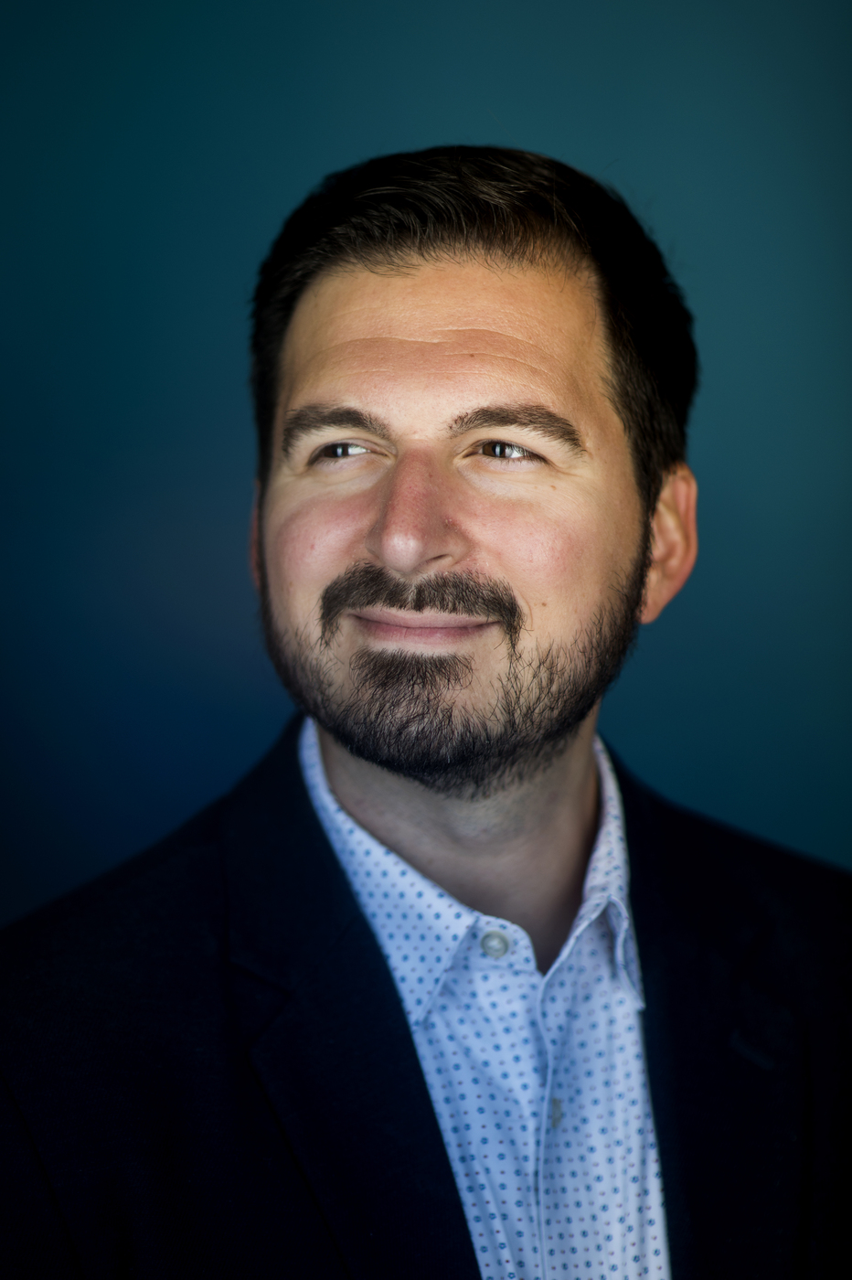 dark haired man with beard wearing button up shirt and suit jacket