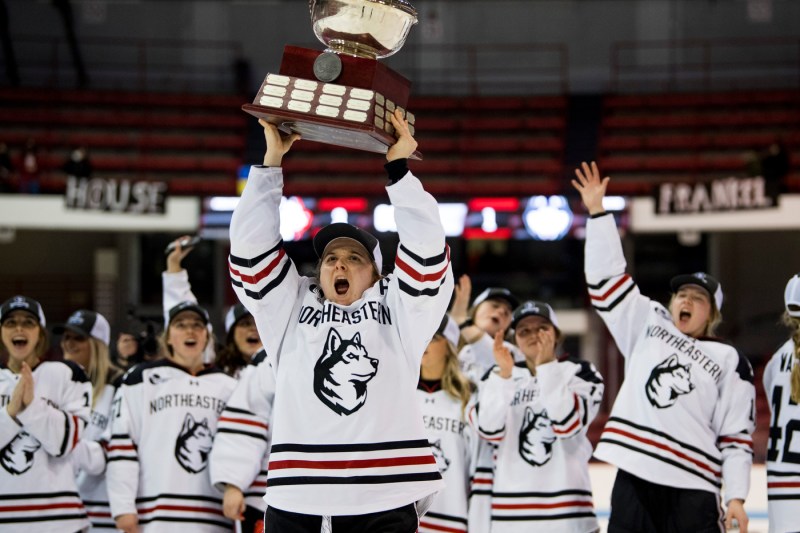 hockey team cheering and holding up trophy