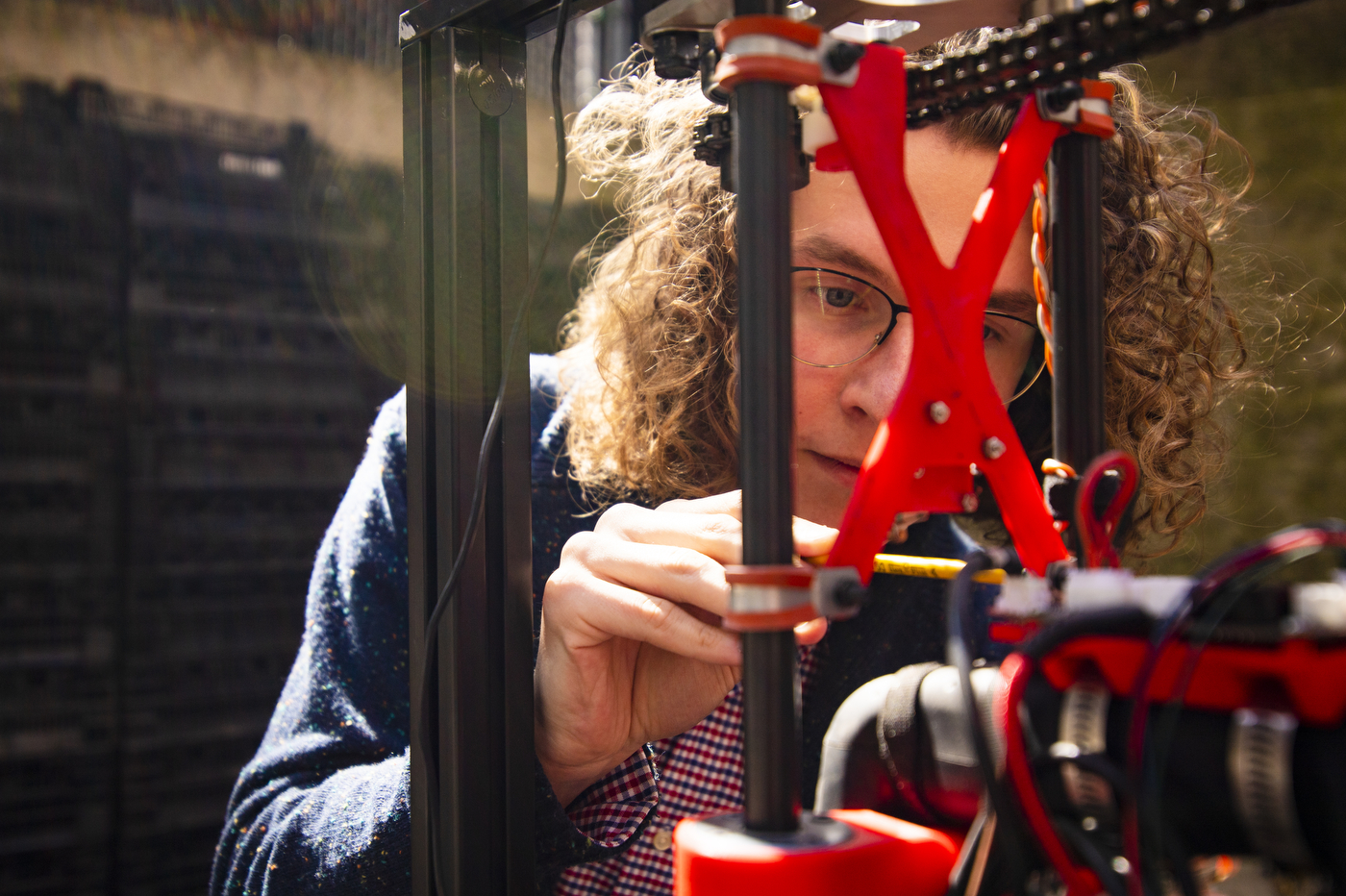 Samuel tightens a screw on the machinery