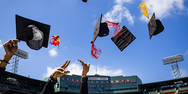 students hands throwing graduation caps in the air