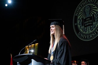 madison mailey standing at podium wearing cap and gown