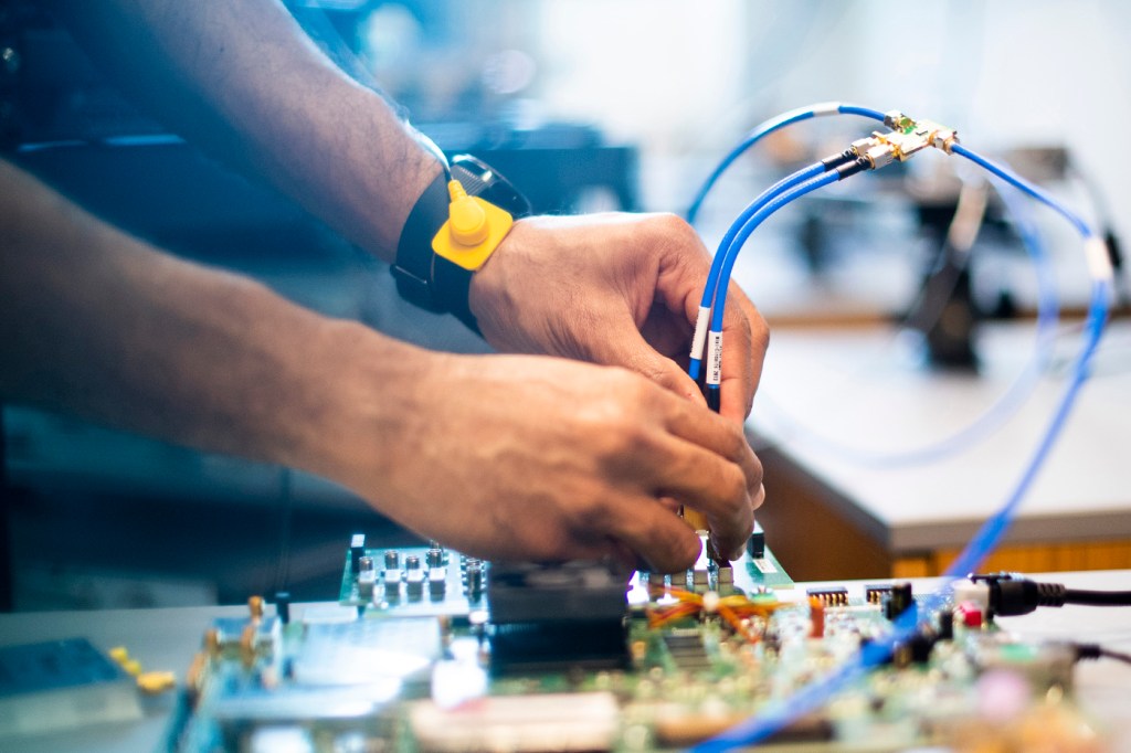 hands holding wires to a circuit board