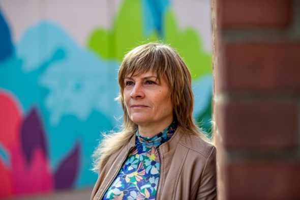 woman waering blue floral shirt and brown jacket