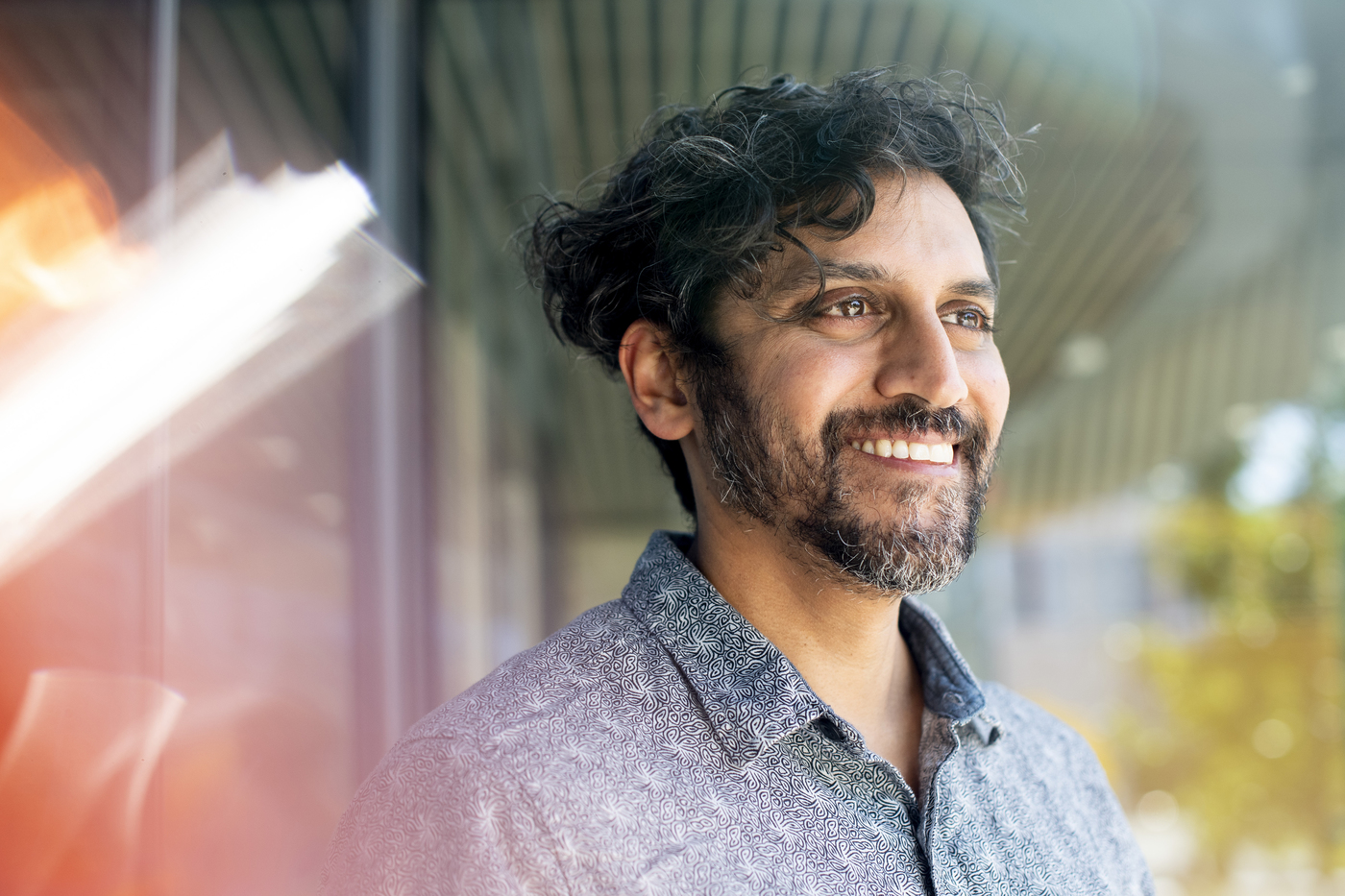 man smiling with dark curly hair and beard