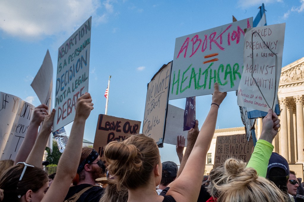 people holding signs at a protest against roe v wade being overturned