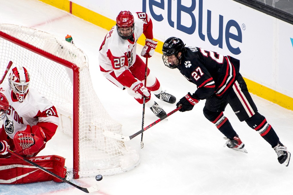 two hockey players skate around the net