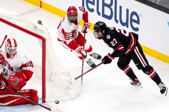 two hockey players skate around the net