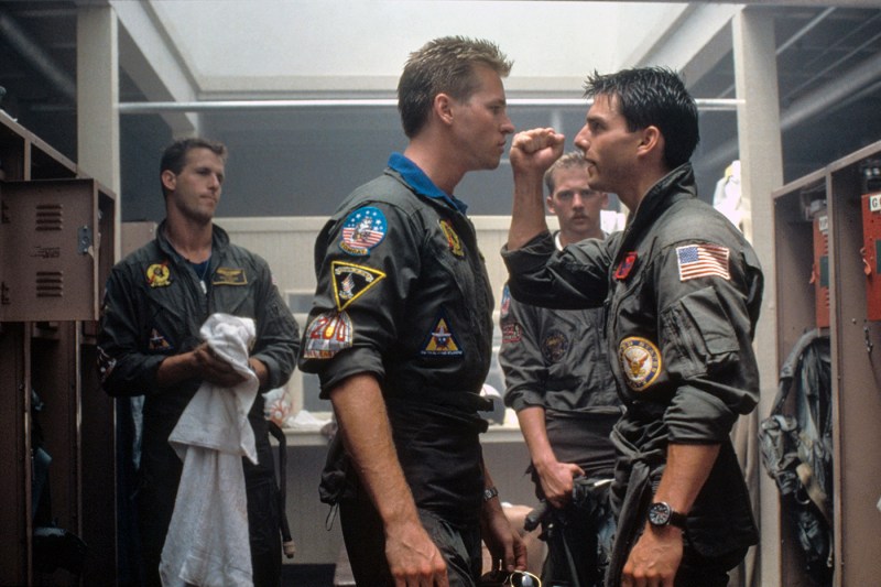 two navy aviators standing face to face, one holding his fist in the area