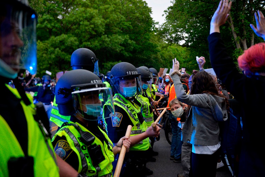 police officers wearing yellow vests and helmets blockade protestors