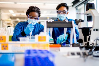 two people in a lab holding lab samples