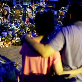 two people standing arm in arm in front of a memorial
