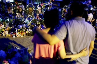 two people standing arm in arm in front of a memorial