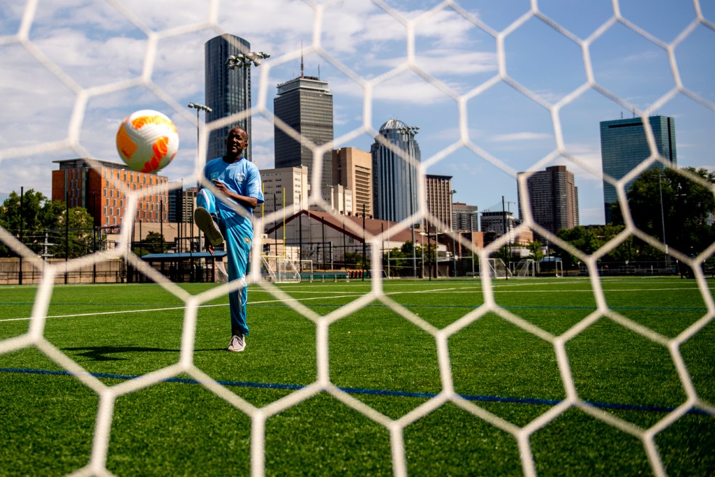 person kicking soccer ball into a net