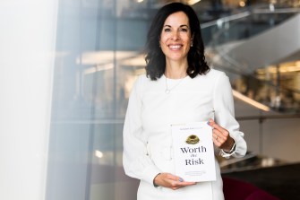 brunette woman wearing all white holds a book