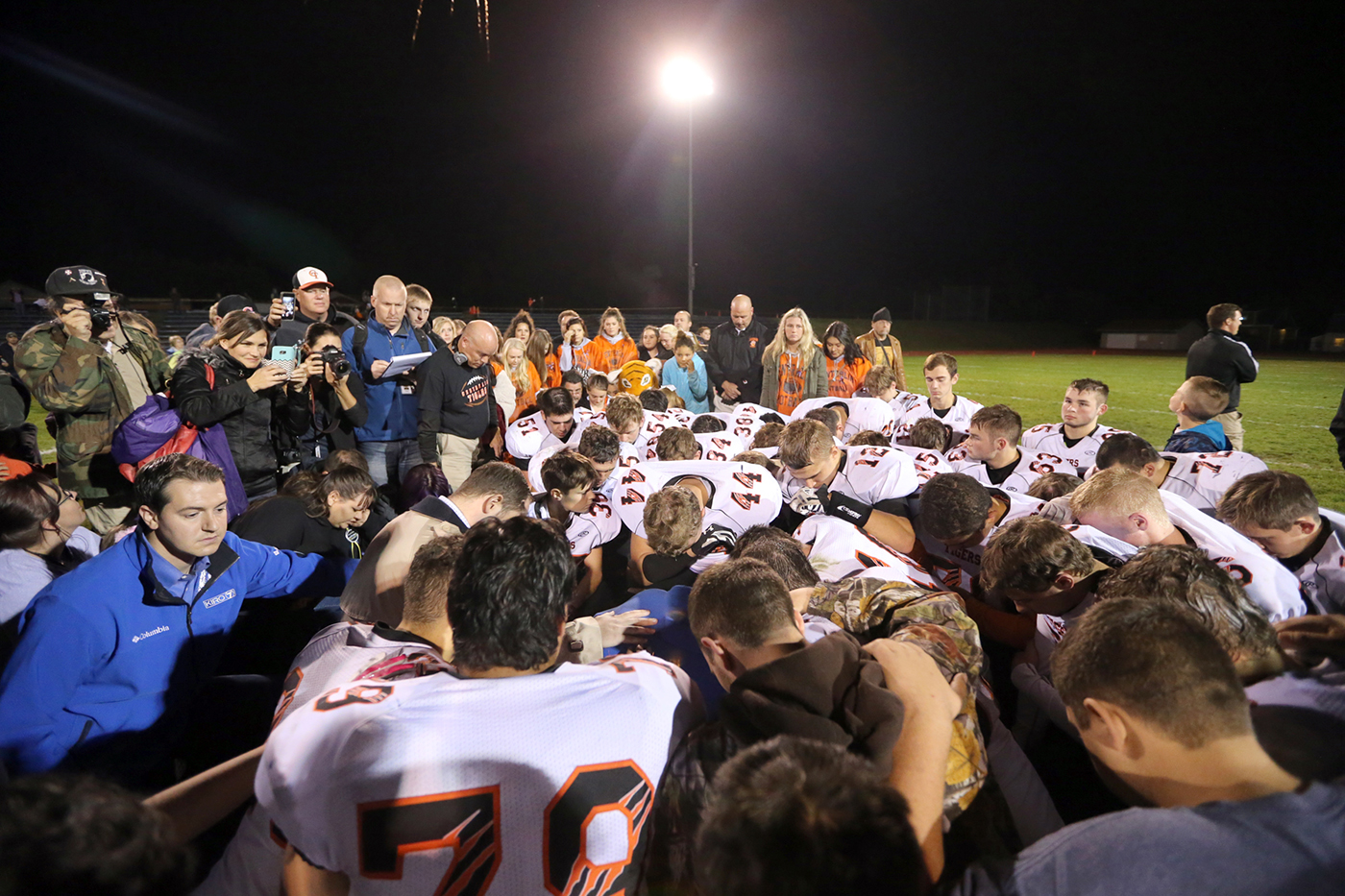 A huddle of football players bowing their heads in prayer