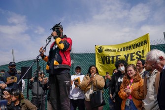 man standing at a microphone surrounded by protestors