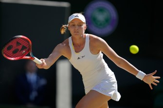 woman wearing all white tennis outfit swinging for a tennis ball