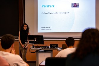 woman standing at the front of a class next to a projector screen