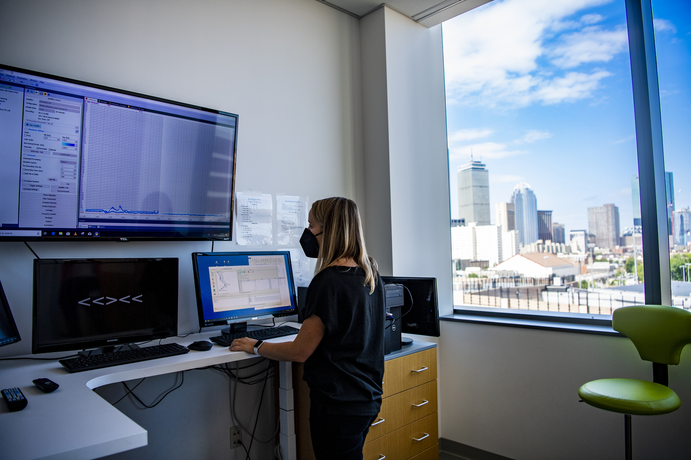 A researchers looks at a large computer screen with charts and data on it