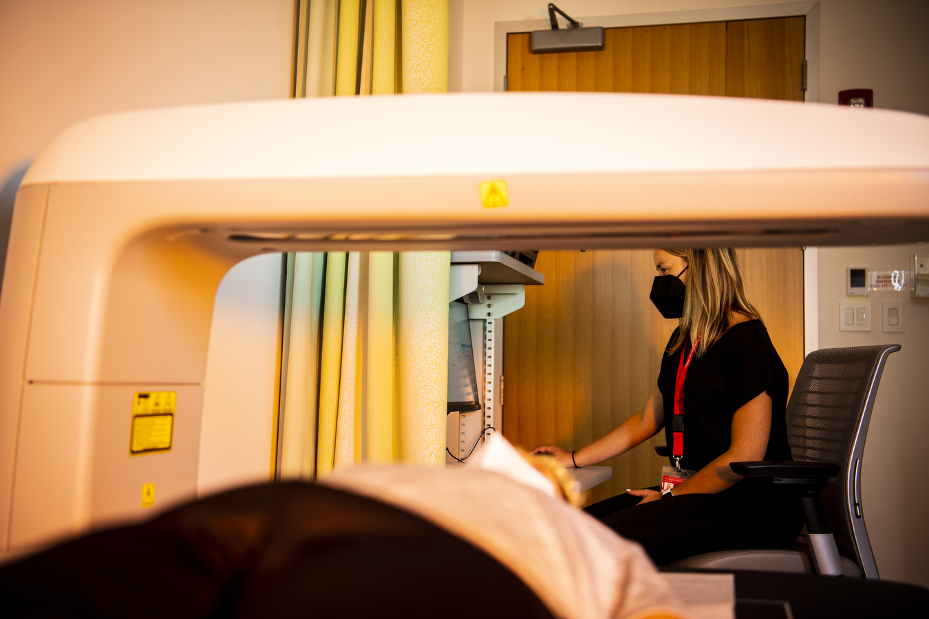 A researcher operates an x-ray machine that a study participant lays underneath