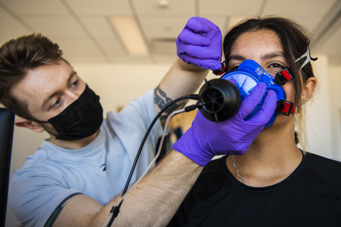 A study participant has their VO2 max desk device adjusted on their face by a researcher