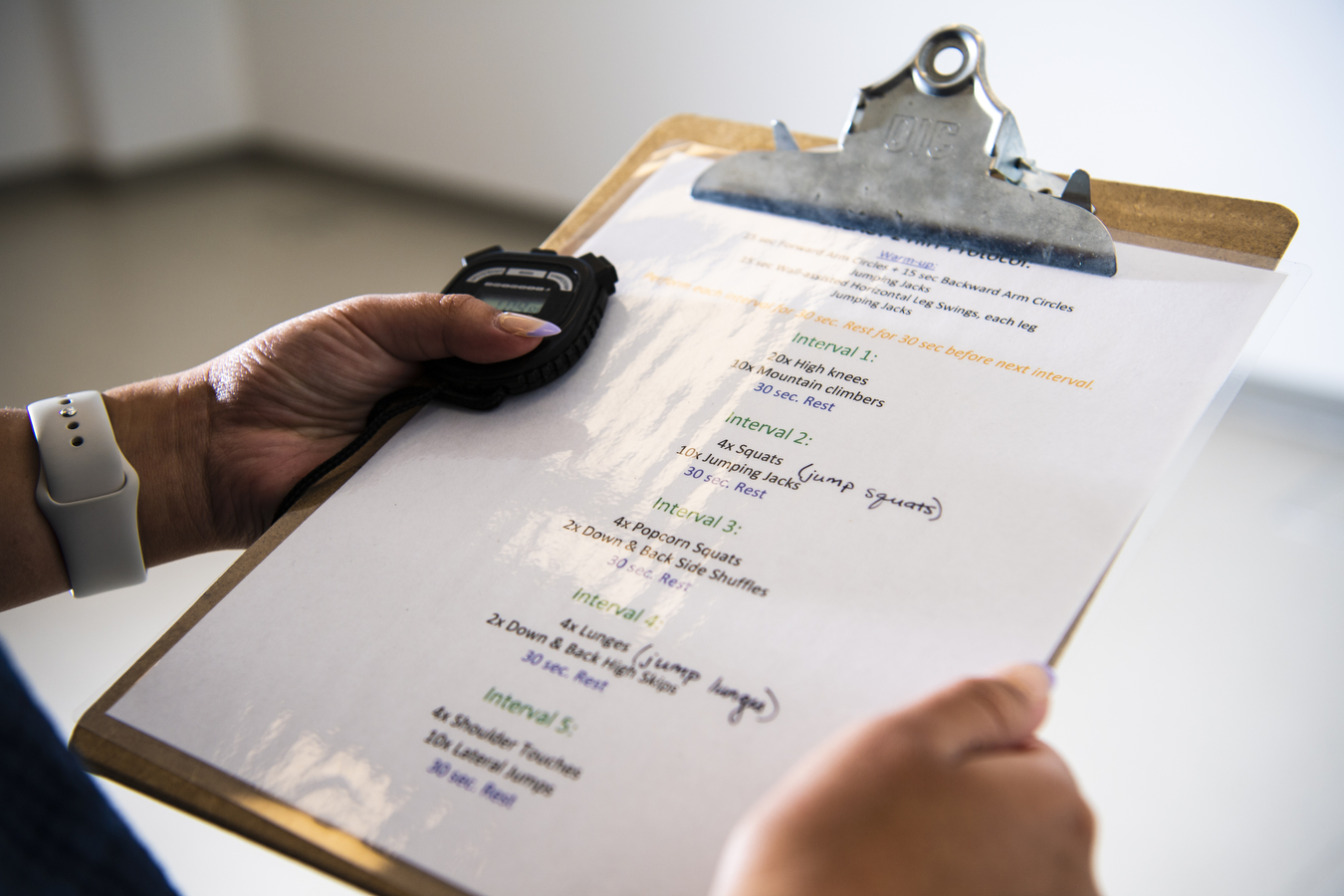 A researcher holds a clipboard and stopwatch in their hands